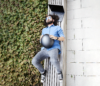 Picture from a guy laying on a wooden bench with a laptop behind his head